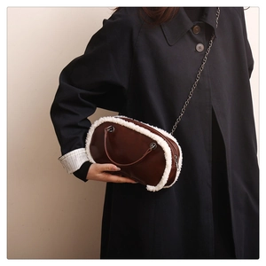 Detail of dark brown chain bag with plush white fur trim on a black coat outfit