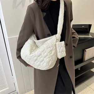 Detail view of white heart-quilted tote bag showing soft texture and mini matching pouch