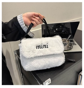 Gros plan du sac bandoulière en peluche blanche avec broderie et sangle noire