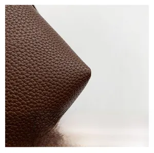 Close-up of high-quality dark brown lychee grain leather texture on a mobile crossbody bag