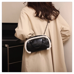 Detail of stylish black leather shoulder bag with white faux fur trim and metal chain strap