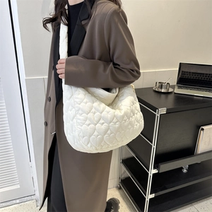 Detail view of white lightweight tote bag featuring heart quilted pattern and soft texture