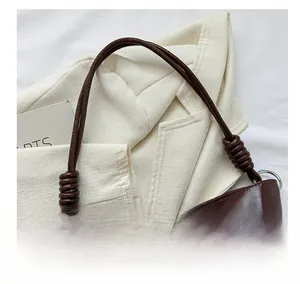 Detail view of the deep brown leather tote bag showing a unique knotted handle and silver rings
