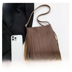Detail view of dark brown tassel shoulder bag with lychee grain texture and silver hardware