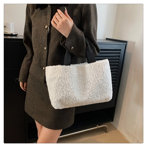Detail of white faux fur tote bag with black fabric handles and plush texture