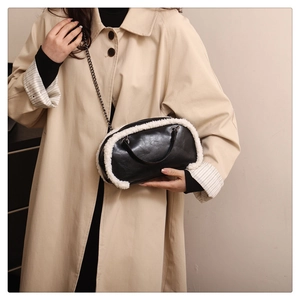 Close-up of black faux leather handbag with white faux fur trim and silver chain strap