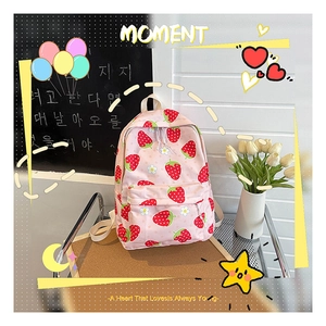 Detailed view of pink school backpack with red strawberry and small white floral patterns