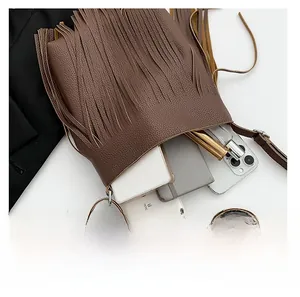 Macro view showing brown litchi pattern leather bag capacity with long tassels