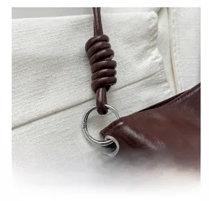 Detail of dark coffee leather bag with silver ring connector and handmade knotted strap