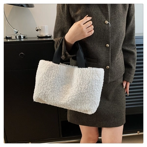 Detail of white faux shearling tote bag with contrasting black handles for winter