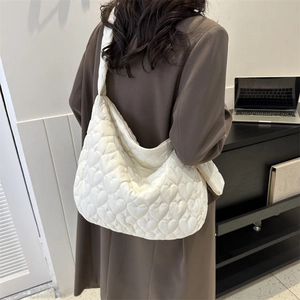 Macro detail of white quilted tote bag featuring stylish 3D heart-shaped stitching