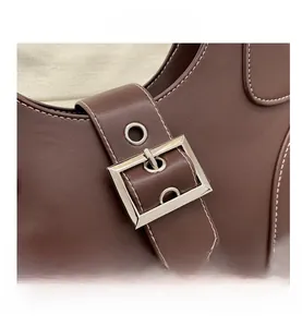 Close-up of deep brown leather bag with silver metal buckle and white contrast stitching
