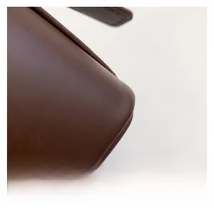 Gros plan des coutures fines et de la texture du cuir marron foncé sur un sac
