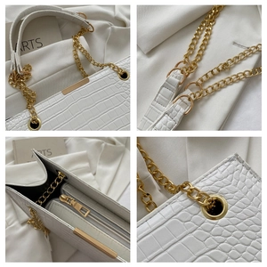 Detail of white crocodile embossed leather bag with gold chain and metal accents