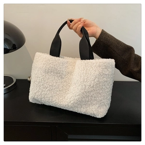 Detailed shot of cream sherpa tote bag with contrast black handles on a minimalist desk
