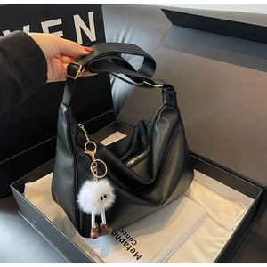 Détail du sac hobo noir à grain litchi avec boucle en métal doré et breloque peluche