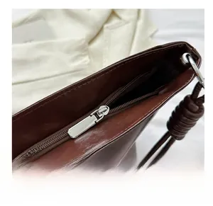 Detailed view of the smooth silver zipper and glossy dark brown leather on tote bag
