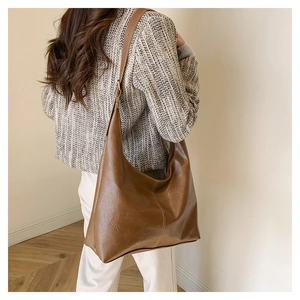 Detail of vintage brown large capacity faux leather hobo bag worn by a model