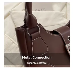 Detailed macro view of deep brown leather handbag with contrast white stitching and metal ring