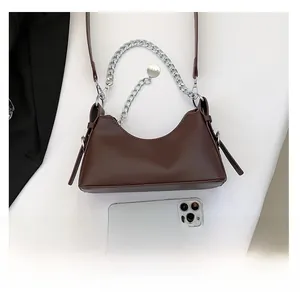 Sac baguette en cuir marron avec chaîne argentée montré à côté d'un téléphone pour taille