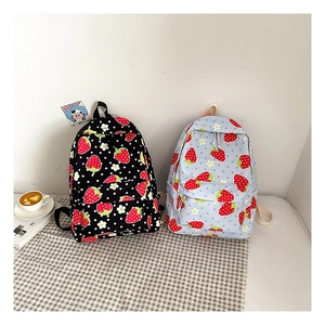 Detail of canvas backpacks with strawberry and daisy patterns in black and light blue colors