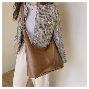 Detail of vintage brown leather hobo bag with vertical stitching and wide strap