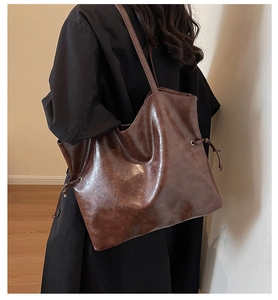 Deep brown bucket tote bag featuring side drawstring detail and minimalist leather finish