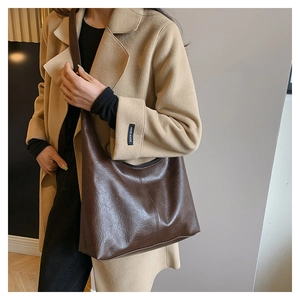 Close-up of vintage dark brown wrinkled leather texture and handle on a hobo shoulder bag