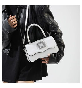 Détail du sac blanc en cuir mat avec boucle en cristal et bordure ondulée originale