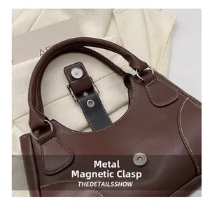Detail of vintage brown leather handbag with white contrast stitching and magnetic buckle
