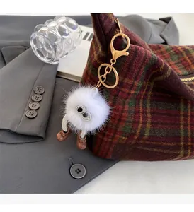 Close-up of a creative plush charm with large eyes attached to a checkered handbag