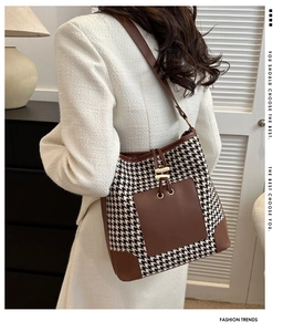 Detail of classic black and white houndstooth pattern with brown leather trim on bag