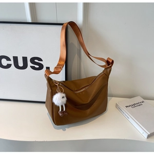 Détail du sac hobo en cuir grainé caramel avec large bandoulière et pendentif en peluche