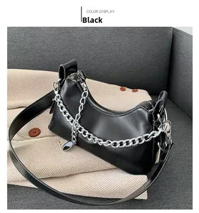 Détail du sac sous l'aisselle noir avec chaîne argentée et bandoulière sur blazer
