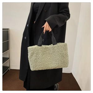 Detail of light green faux shearling tote bag with contrasting black woven handles
