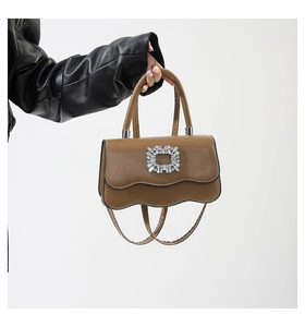 Détail du sac en cuir caramel avec rabat à bords ondulés et boucle carrée en cristal