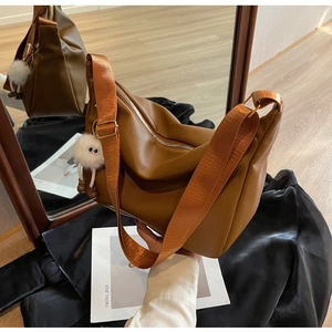 Détail du sac hobo marron avec bandoulière orange et pendentif en peluche