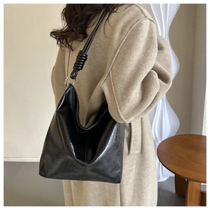 Detail of black PU leather hobo bag featuring a unique knotted shoulder strap and silver ring