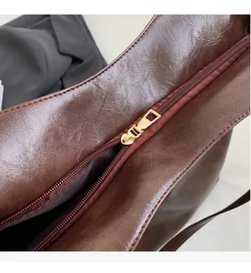 Close-up of smooth gold zipper on high-quality dark brown leather tote bag detail