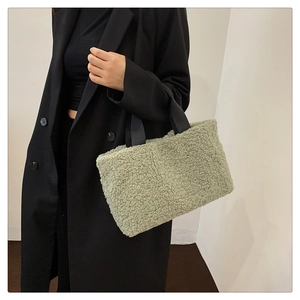 Detail view of sage green plush lambskin tote bag carried by model in casual outfit
