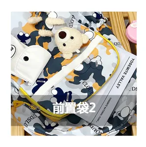 Close-up of camo backpack front pocket with cute plush bear charm and CLOUD logo print