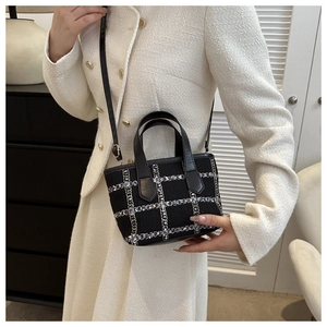 Detailed close-up of small black tweed tote bag with classic blue and white plaid pattern