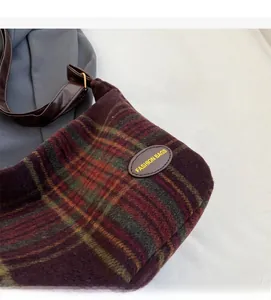 Detail shot of vintage plaid crossbody bag featuring wool-like fabric and leather logo patch