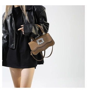 Détail du sac en cuir marron vintage avec bords ondulés et boucle en cristal brillant