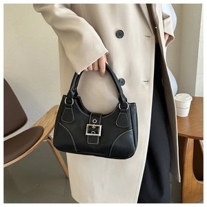 Detail of a vintage black leather handbag with white contrast stitching and silver buckle