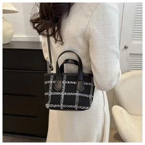 Detail view of the black plaid wool tote bag with leather handles and adjustable strap