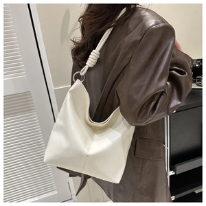 Detail of minimalist cream hobo tote bag with unique knot strap and metallic hardware