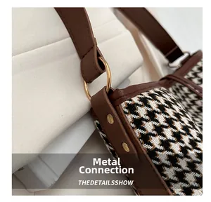 Detail of golden metal ring and rivets on houndstooth fabric with brown leather trim