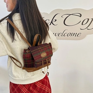 Close-up of red and green plaid woolen backpack with brown leather details and FEIMU logo