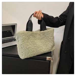 Close-up of soft bean green fleece tote bag with black strap in a modern office setting